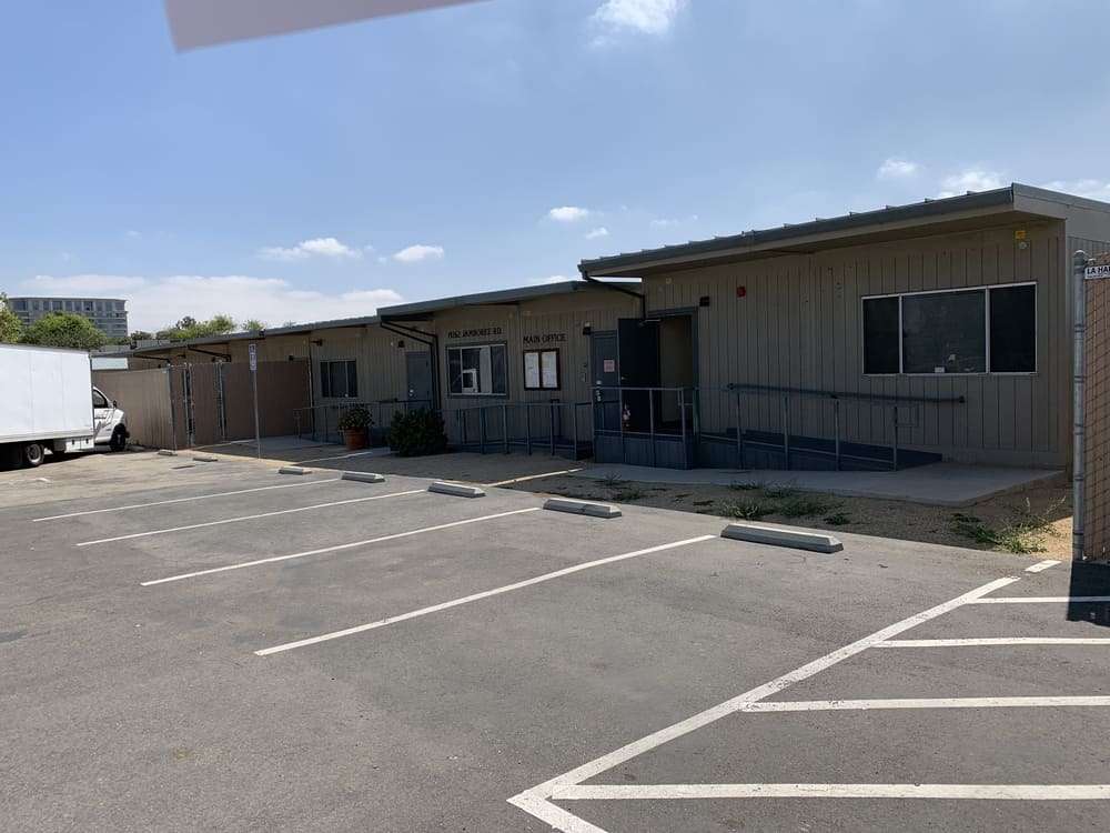Front elevation of modular office buildings with ramps and an empty parking area.
