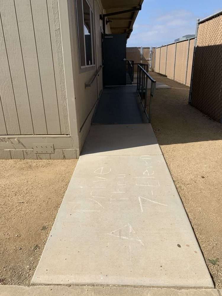 Concrete walkway and access ramp beside a modular building.