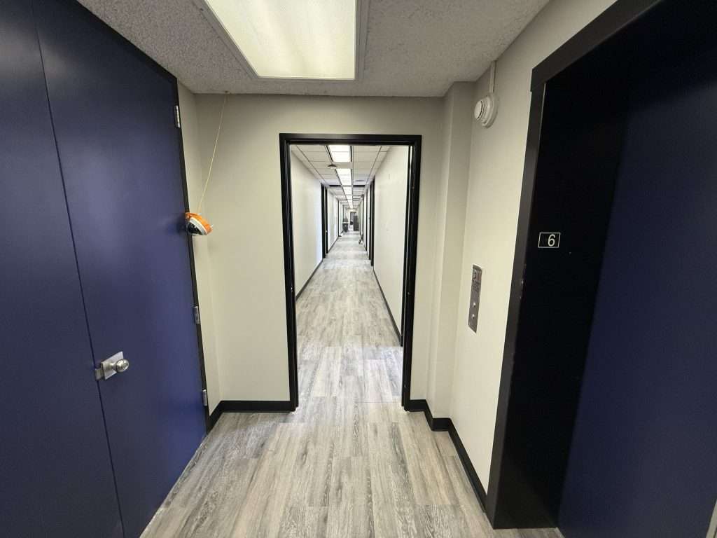 Completed municipal office corridor with new flooring, painted walls, wall base and refinished doors.