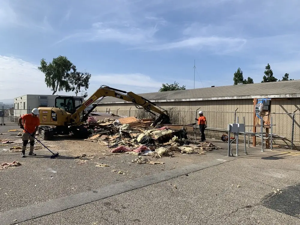 Excavator and crew clearing demolition debris at a Southern California site