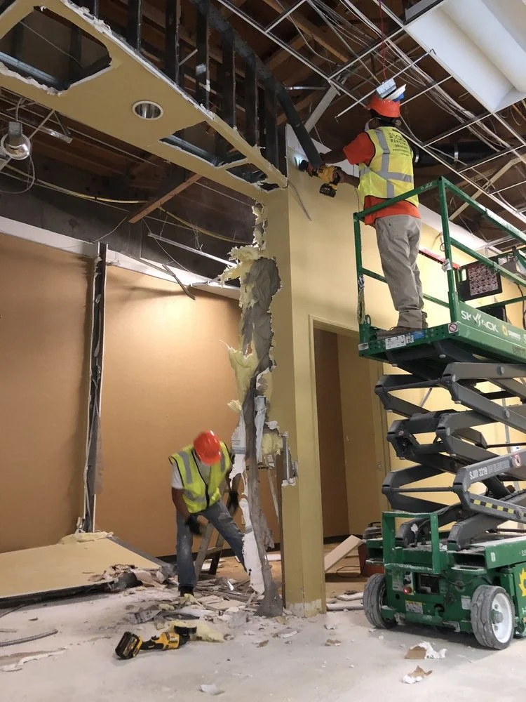 SoCal Removal crew removing interior wall and ceiling components from a defined work area using lift access