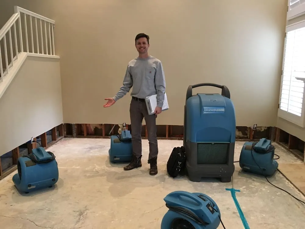 Worker beside air-moving equipment in an interior room with lower wall sections removed