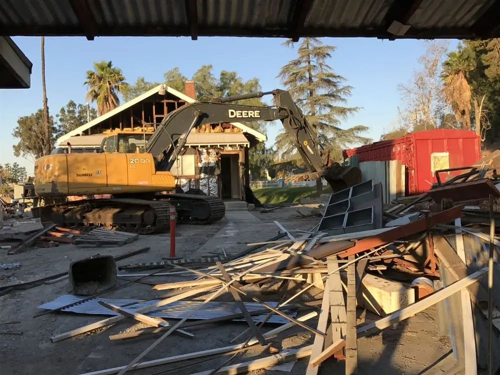 Excavator and segregated building materials within a structure-removal work area
