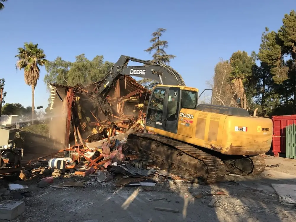 Tracked excavator removing a wood-framed structure